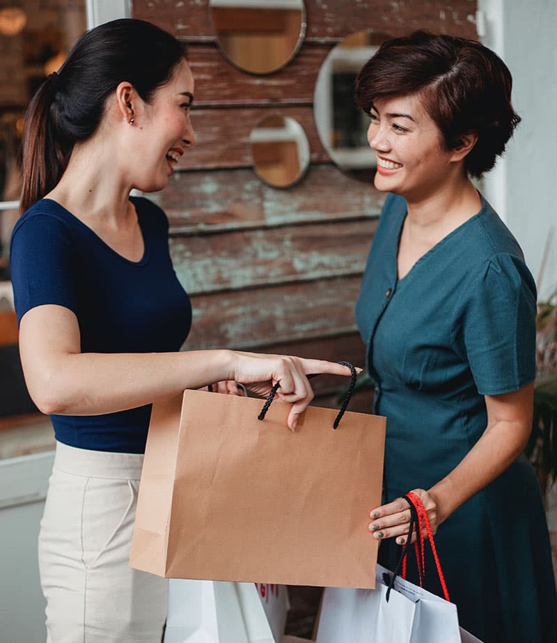A salesperson in a store laughing together with a customer who just made a purchase.