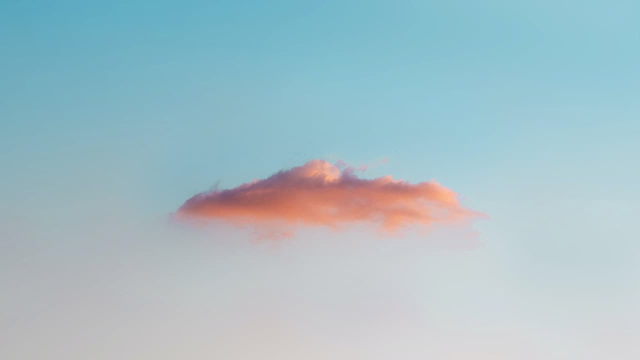 A small pink cumulus cloud against a gradient sky from blue to coral