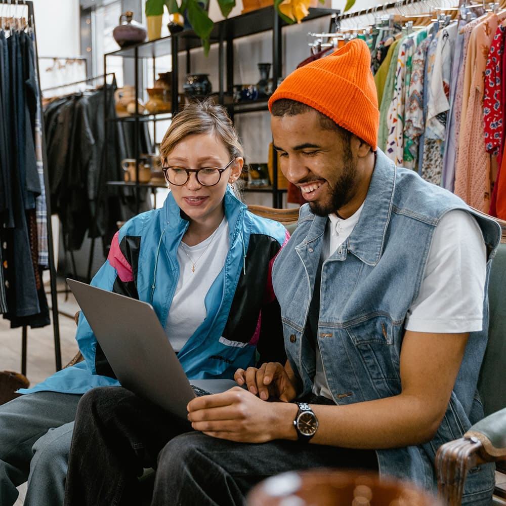 A store employee and his manager sitting in the store after hours, following up on information and training completion on a laptop.