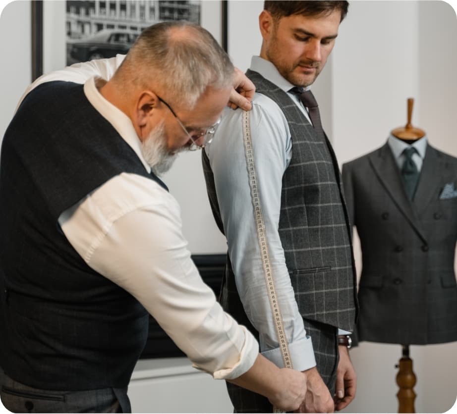 A knowledgeable store salesperson helping a customer measure sleeve length for a suit fitting.