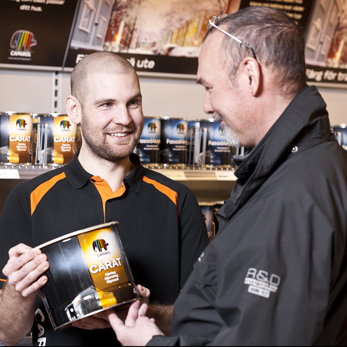 Store employee showing Caparol Carat paint to a customer