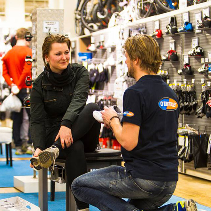 Store employee showing a shoe to a customer trying on new shoes